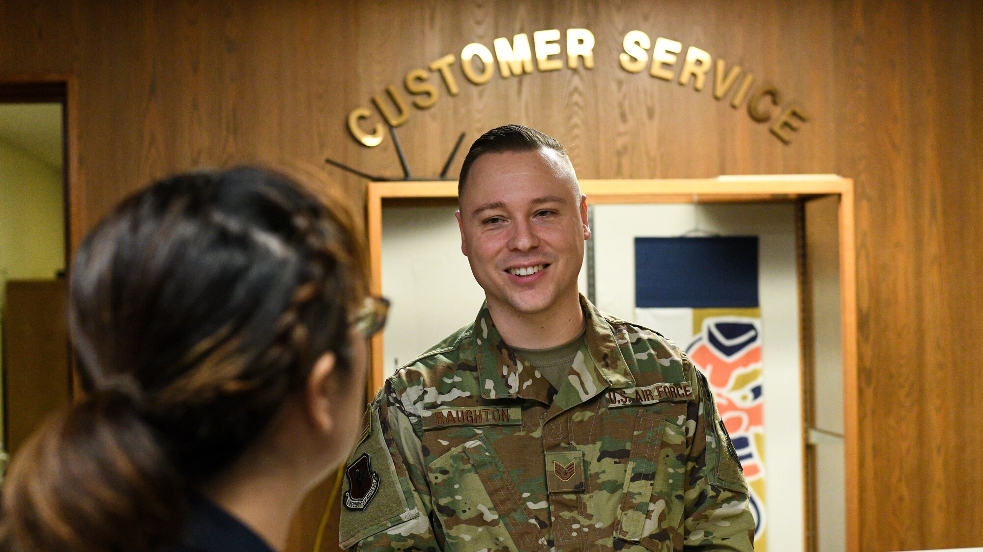 U.S. Air Force Staff Sgt. Benjamin Raughton, 18th Wing Public Affairs photographer, greets a Japanese customer at Kadena Air Base, Japan, Jan. 8, 2020. Raughton's ability to communicate in Japanese with the local population stems from the video games that now rest in his office. (U.S. Air Force photo by Tech. Sgt. Hugo Delgado)