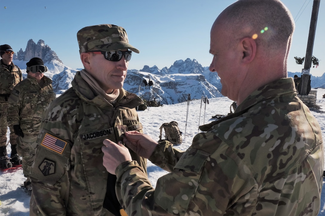 U.S. Army Reserve Lt. Col. Cory D. Poppe, 2500th Digital Liaison Detachment, 7th Mission Support Command, pins rank on Sgt. 1st Class Mark Jacobson, 2500th DLD, 7th MSC, in a mountain-top promotion ceremony after his unit used snowshoes to summit Monte Specie during winter survival training with the Italian Army´s 6th Alpine Regiment during exercise Alpine Rock in Toblach, Italy, January 11, 2020. Fifteen Soldiers from the 2500th participated in the winter survival training that emphasized small-unit tactical interoperability.