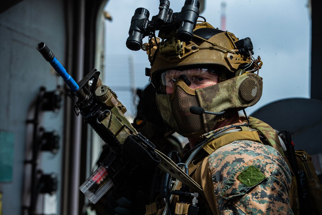 A Marine wearing a mask and holding a gun performs security training.