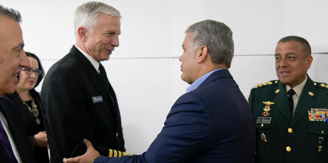 Navy admiral shakes hands with a man dressed in a suit.