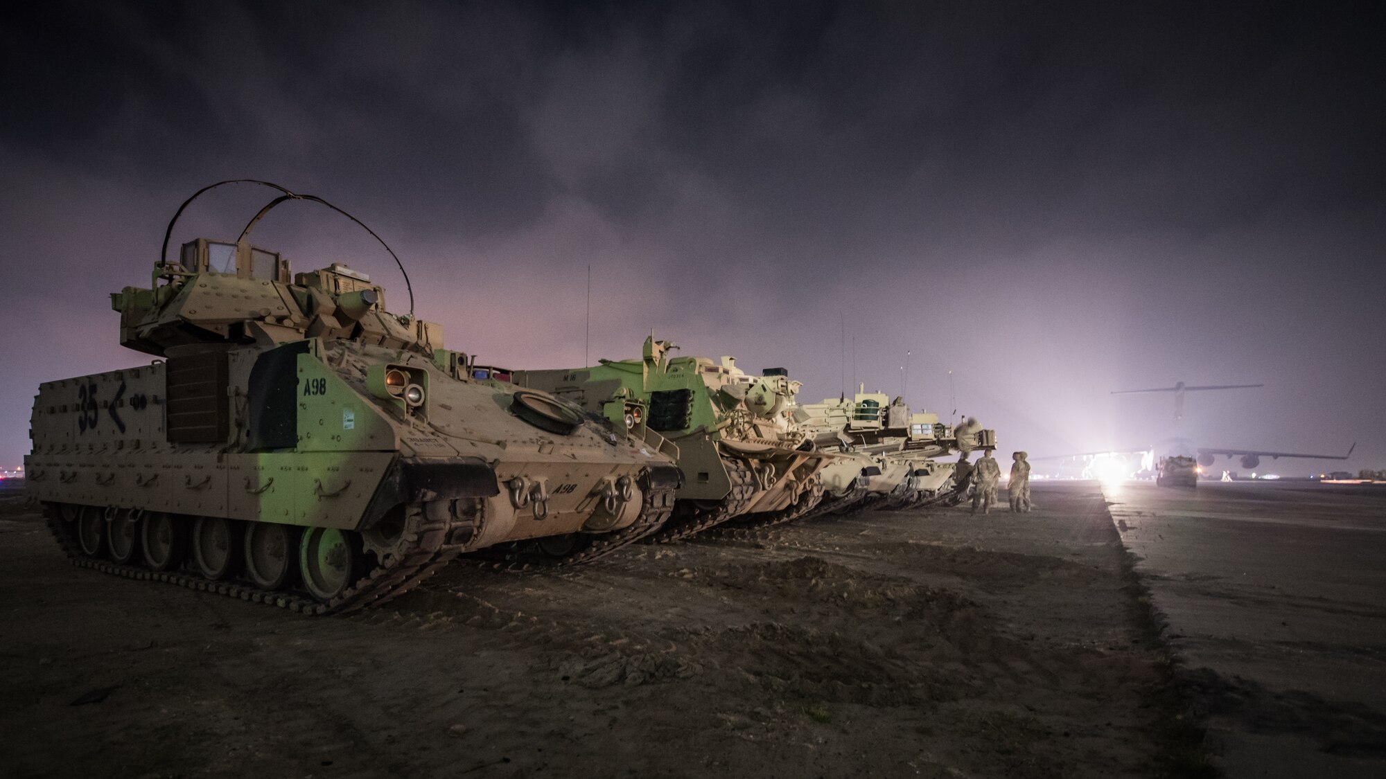 U.S. Army M2 Bradley Fighting Vehicles and M1A1 Abrams tanks are parked next to a flight line in the U.S. Central Command area of responsibility, Jan. 3, 2020. USCENTCOM directs and enables military operations and activities with allies and partners to increase regional security and stability in support of enduring U.S. interests. (U.S. Air Force photo by Tech. Sgt. Daniel Martinez)