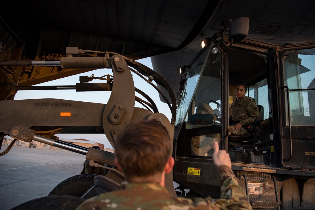 A U.S. Air Force aerial porter assigned to the 746th Expeditionary Logistics Readiness Squadron and a U.S. Air Force loadmaster assigned to the 746th Expeditionary Airlift Squadron communicate while loading cargo into a C-130 Hercules in the U.S. Central Command area of responsibility, Jan. 8, 2020.