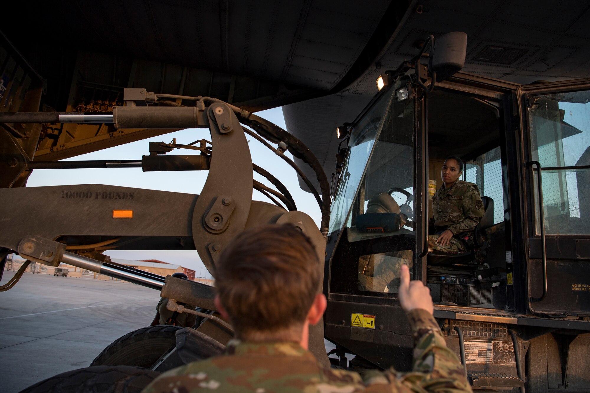 A U.S. Air Force aerial porter assigned to the 746th Expeditionary Logistics Readiness Squadron and a U.S. Air Force loadmaster assigned to the 746th Expeditionary Airlift Squadron communicate while loading cargo into a C-130 Hercules in the U.S. Central Command area of responsibility, Jan. 8, 2020.