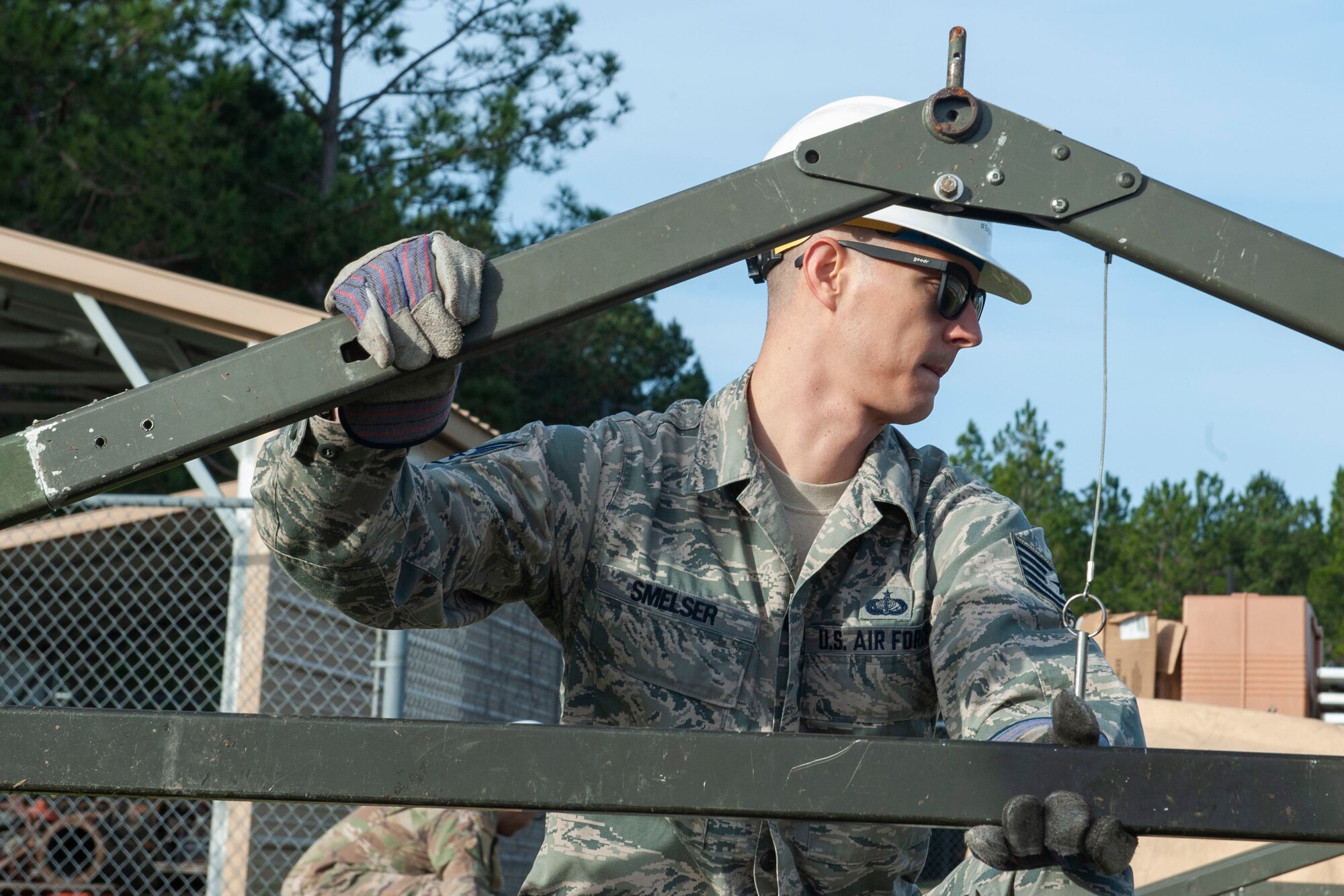 Photo of an Airman holding tent structure parts