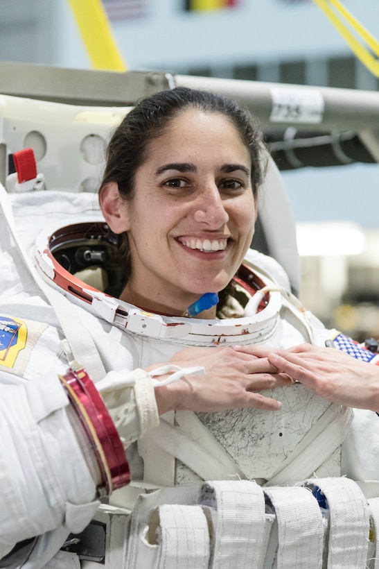 An astronaut candidate wearing a spacesuit without the helmet smiles.