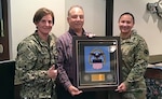 A DLA civilian receives an award from commander and deputy commander.