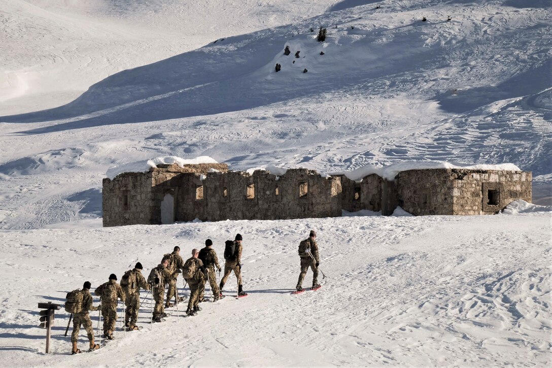 A group of soldiers climbs a snowy mountain.