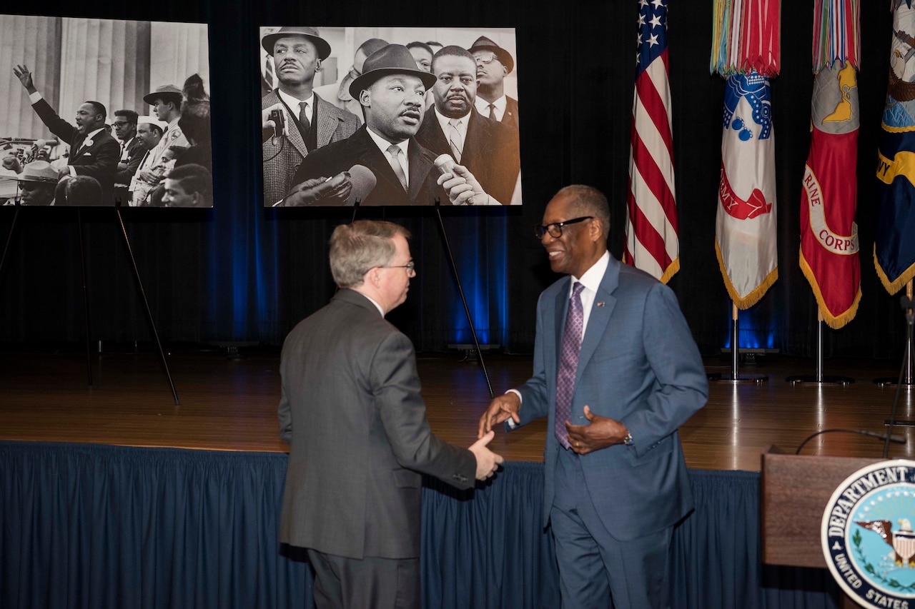 Two men shake hands.