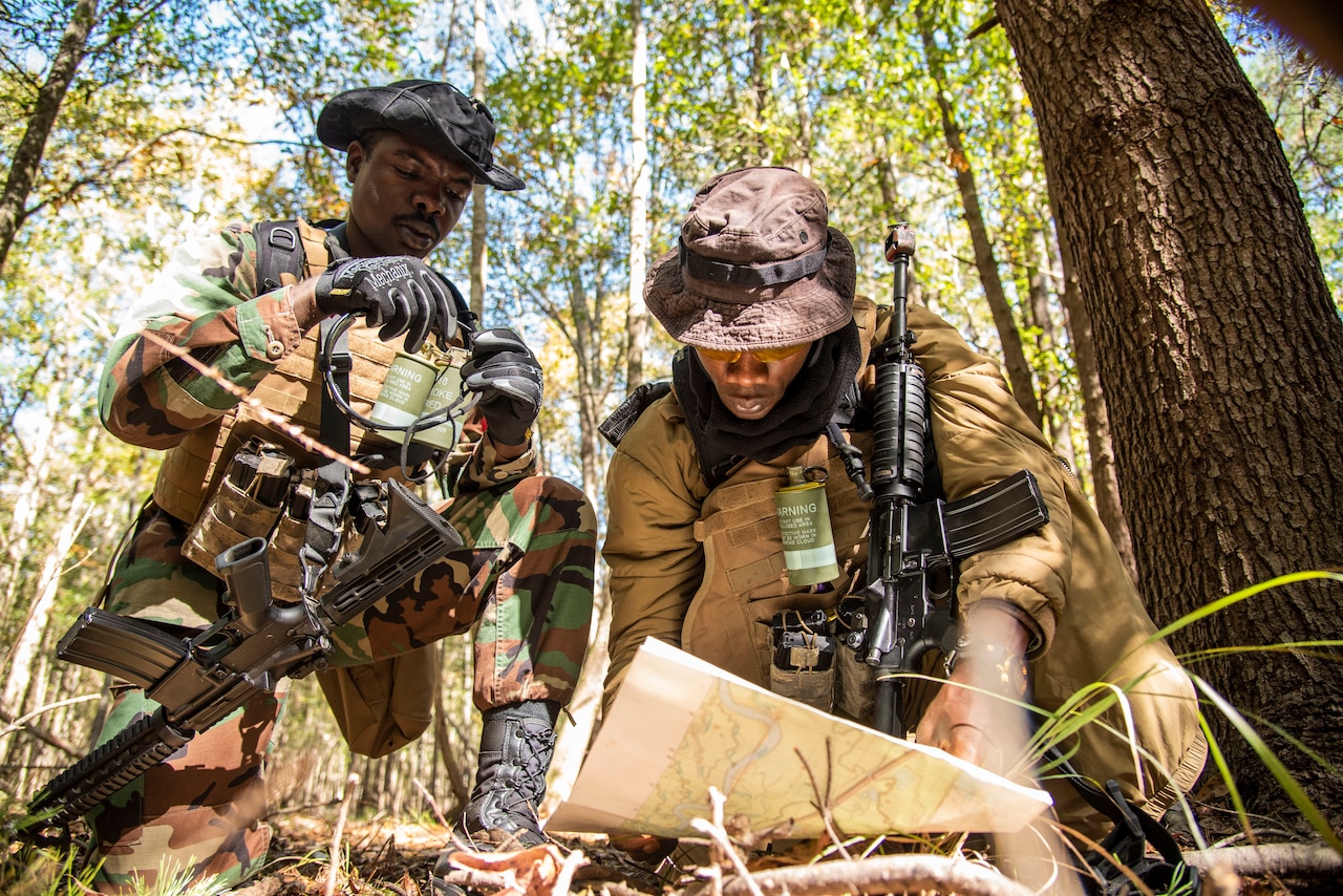 Two men in camouflage uniforms look at a map.