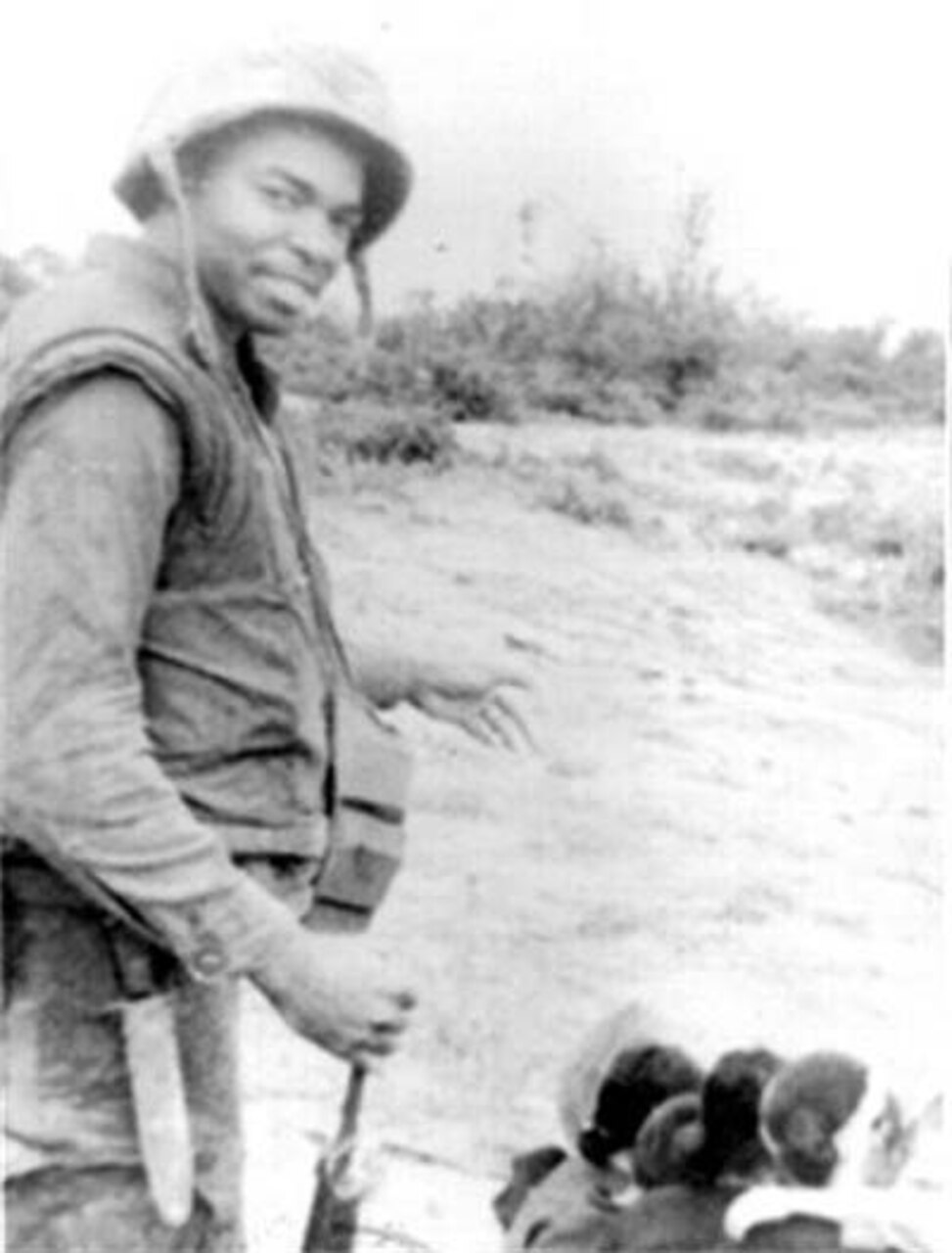 A Marine wearing a vest, utility uniform and helmet looks at the camera.