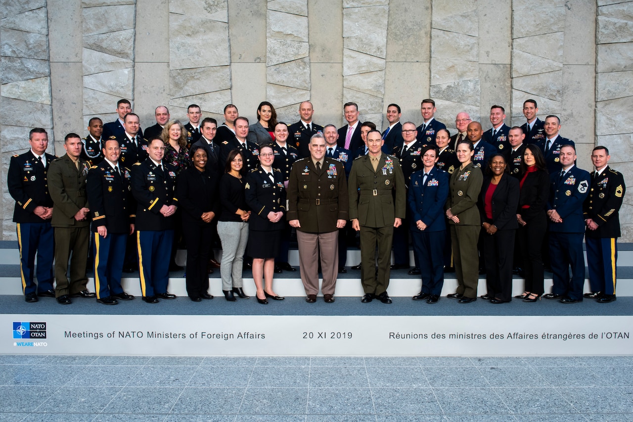 About 30 people stand in three lines posing for a photograph.