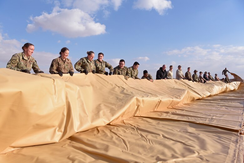 Airmen unroll a fuel bladder