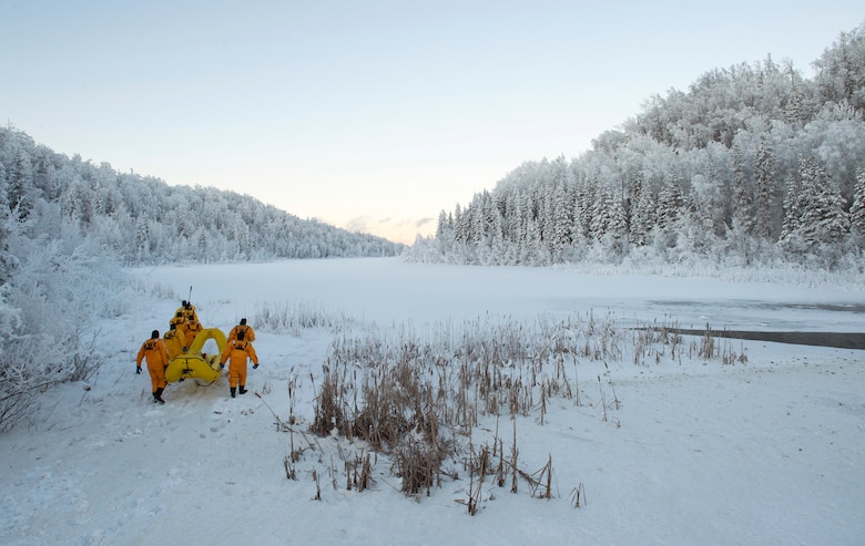Air Force fire protection specialists make their way toward a frozen lake during ice-rescue training