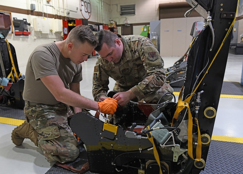 Airman 1st Class Robert Dumbeck (left), 9th Maintenance Squadron aircrew egress systems journeyman, and Tech. Sgt. Cody Clark 9th MXS aircrew egress systems craftsman, inspect an egress seat D-ring before installing a D-ring guard, Jan. 16, 2020 at Beale Air Force Base, California. When a pilot pulls the D-ring, it fires an initiator that sends gas pressure to explosives. Each of these explosives fire at different items like the lap belt, inertia reel, and foot retractors. (U.S. Air Force photo by Airman 1st Class Luis A. Ruiz-Vazquez)