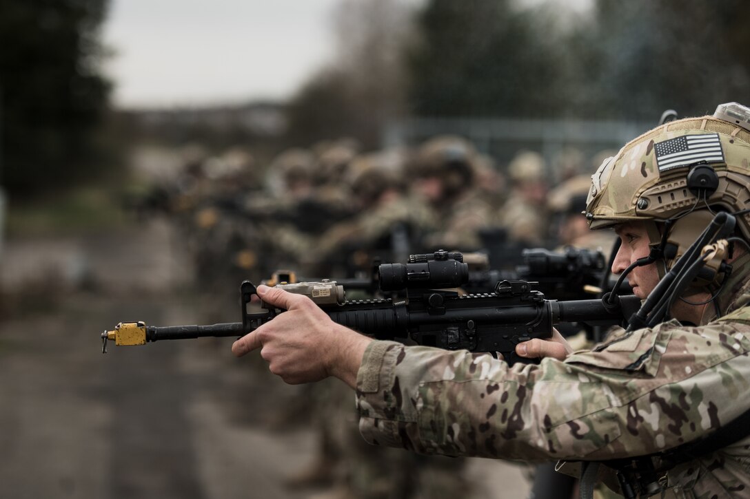 An airman points a rifle; others stand behind.