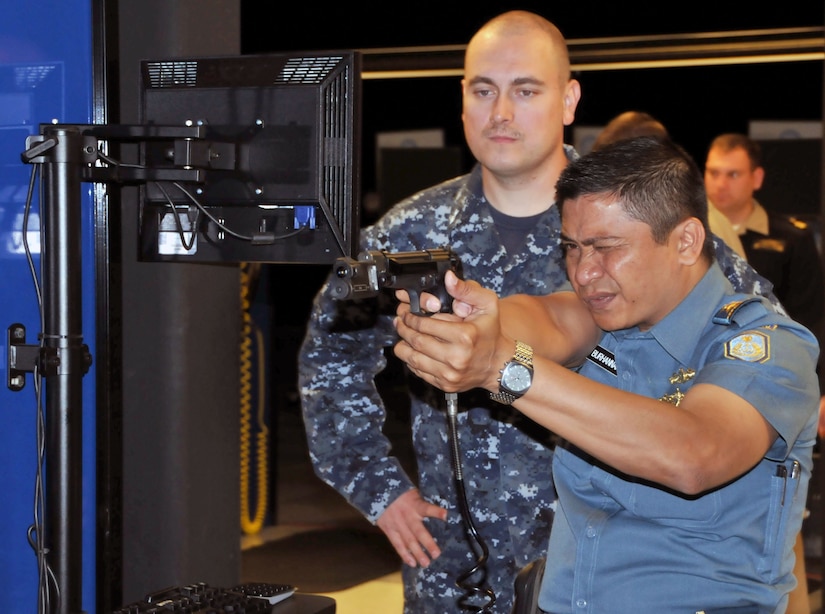A forign service member aims a pistol.  Another watches