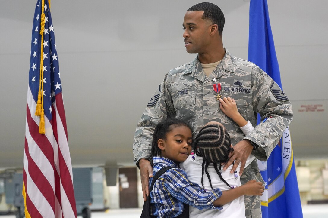 Master Sgt. and his children during a ceremony awarding him the Bronze Star Medal