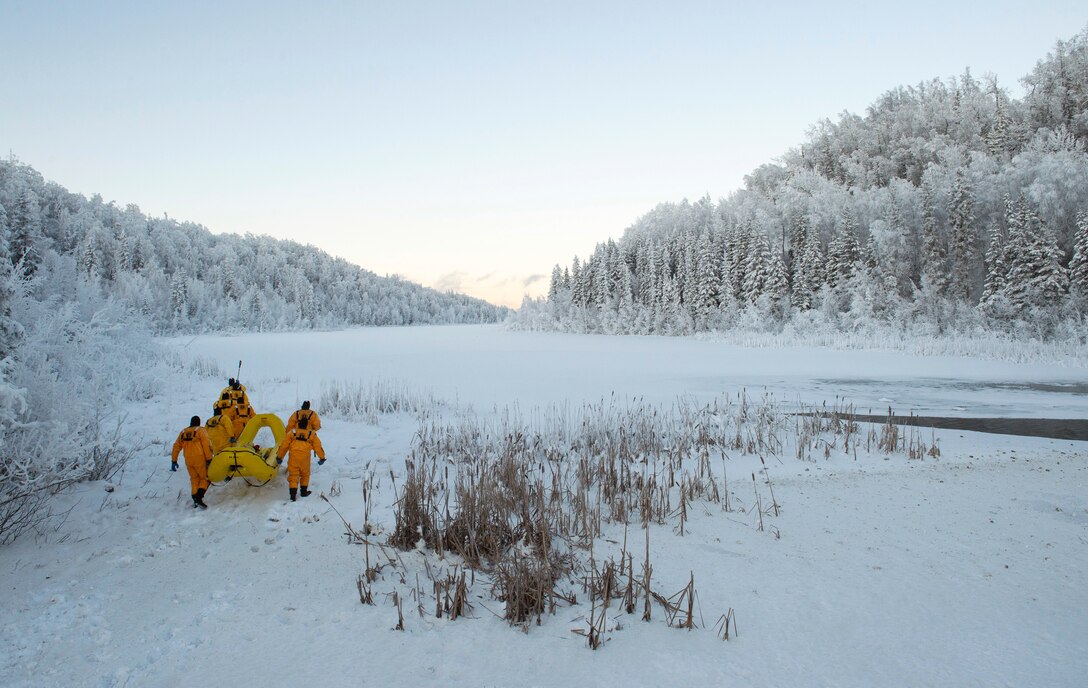 Air Force fire protection specialists make their way toward a frozen lake during ice-rescue training