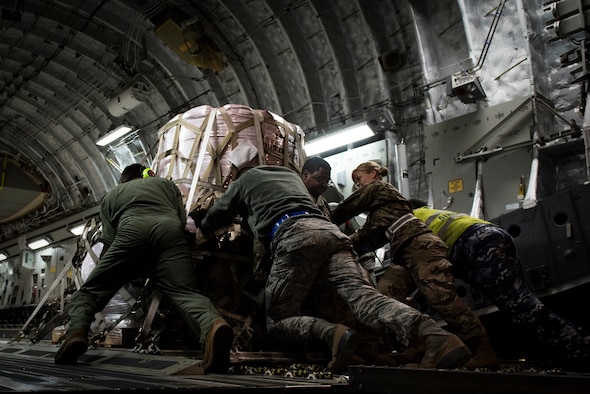 Airmen and RAAF Airmen push fire suppressant on to aircraft.