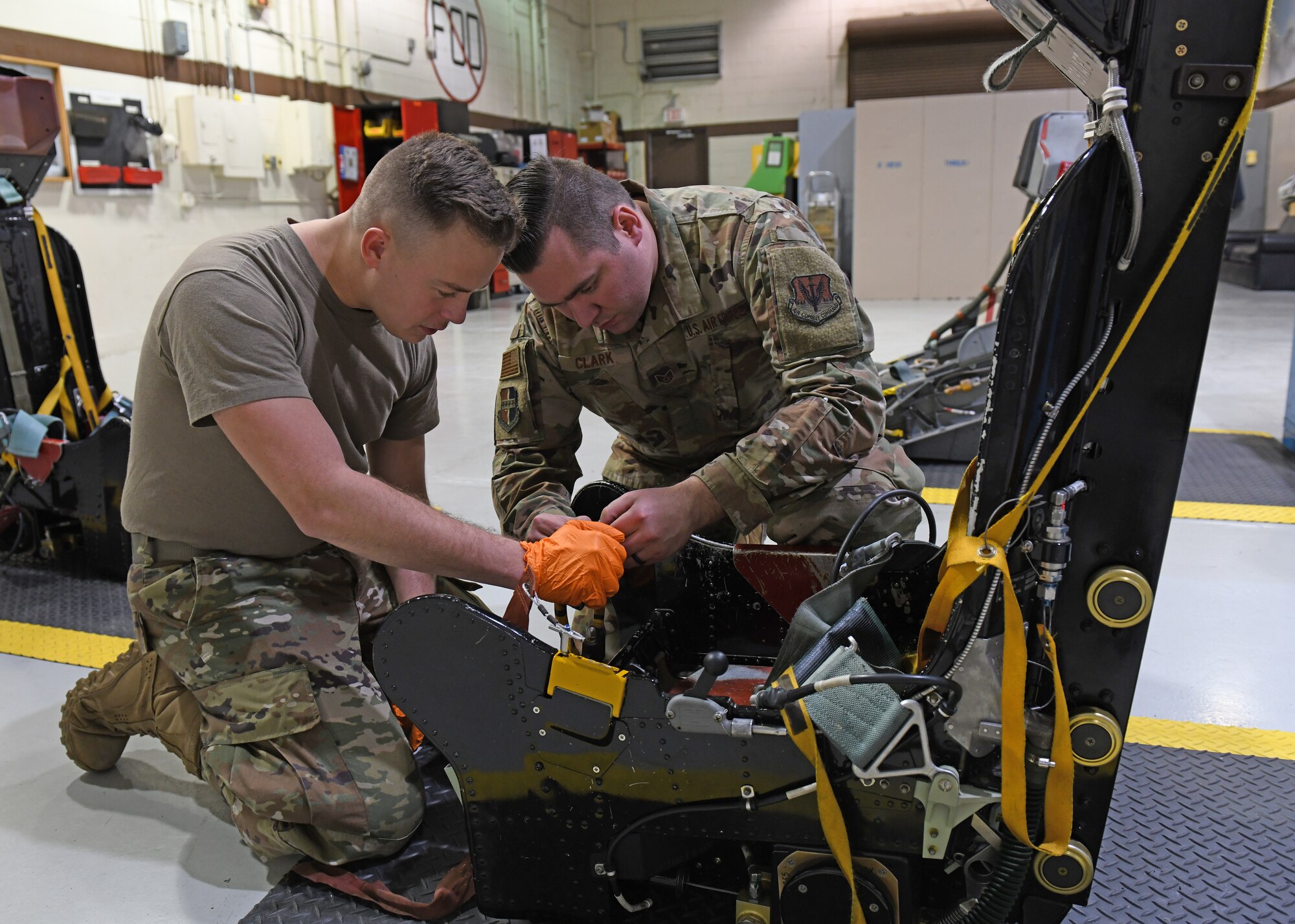 Airman 1st Class Robert Dumbeck (left), 9th Maintenance Squadron aircrew egress systems journeyman, and Tech. Sgt. Cody Clark 9th MXS aircrew egress systems craftsman, inspect an egress seat D-ring before installing a D-ring guard, Jan. 16, 2020 at Beale Air Force Base, California. When a pilot pulls the D-ring, it fires an initiator that sends gas pressure to explosives. Each of these explosives fire at different items like the lap belt, inertia reel, and foot retractors. (U.S. Air Force photo by Airman 1st Class Luis A. Ruiz-Vazquez)