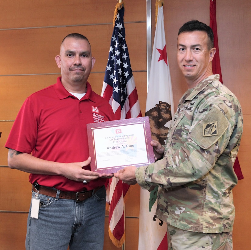 Andrew Rios, administrative support assistant for the U.S. Army Corps of Engineers, left, receives the Helping Hands for Others Award from Col. Aaron Barta, LA District commander, right, during the Fourth Quarter Awards Ceremony Jan. 10 at the LA District’s Headquarters building in downtown LA. Rios received the award while working as an administrative support assistant with the Programs and Project Management Division, for coaching he provided to the division staff to ensure training was completed.