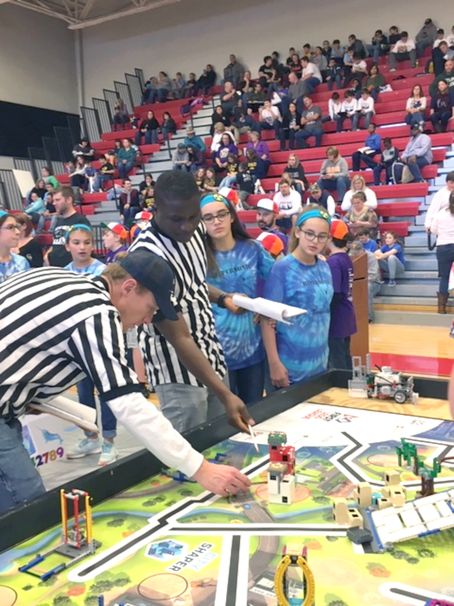 Hypersonic Narwhals team members Karina and Kolleen Roessig, at right, pay close attention as 2nd Lt. Kodjovi Klikan, pictured second from left, an Arnold Engineering Development Complex team member at Arnold Air Force Base, reviews the score with a fellow referee at the regional qualifying tournament at Coffee County Middle School in December. Erin Geraghty and Felicia Goins, the other members of the Hypersonic Narwhals, look on. (Courtesy photo)