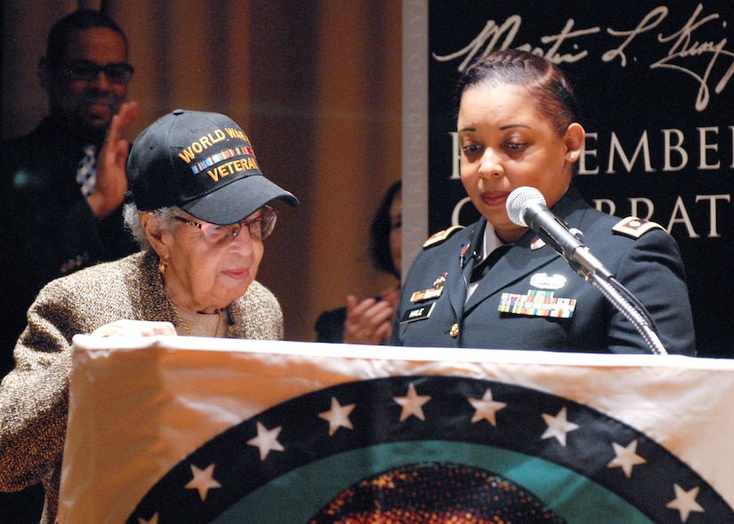 Maj. Lakisha Hale-Earle, chief of G1 plans and training for U.S. Army Reserve’s 99th Readiness Division (right), pays tribute to former Sgt. Hilda P. Griggs, who served in the Second World War’s 6888th Central Postal Directory Battalion (left), during New Jersey’s annual Martin Luther King Jr. commemoration Jan. 19 at the N.J. State Museum Auditorium in Trenton. The 6888th was the first-and-only all-African American, all-female unit to deploy overseas during the war. It consisted of 855 women under the command of Lt. Charity Adams, the first African-American woman commissioned in the Women’s Army Corps. (U.S. Army photo by Sgt. Sal Ottaviano)