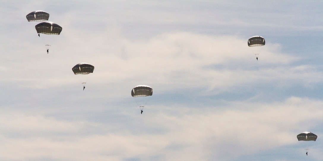 Six soldiers descend under open parachutes.