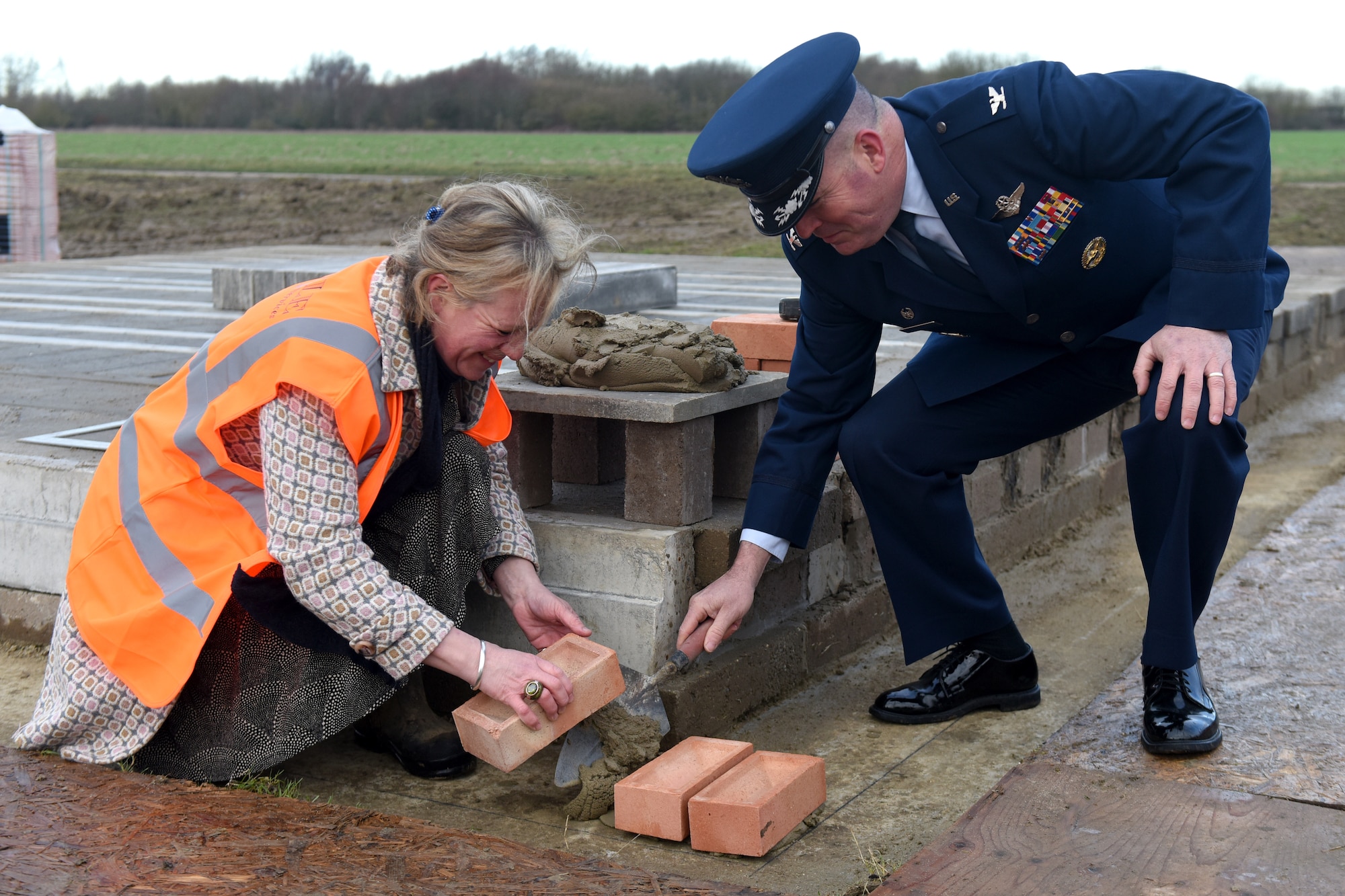 Col. Will Marshall, 48th Fighter Wing commander, helps lay down a brick with Alice Pawsey, land owner of Lavenham Airfiled, at Lavenham Airfield, England, Jan. 20, 2020. Marshall visited Lavenham Airfield to help lay down the first brick for a long-lasting memorial honoring 233 U.S. military service members that died in World War II. (U.S. Air Force photo by Airman 1st Class Madeline Herzog)