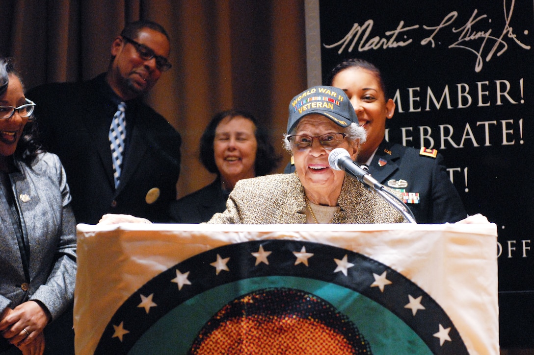 A veteran speaks at a lectern while four other people look on.