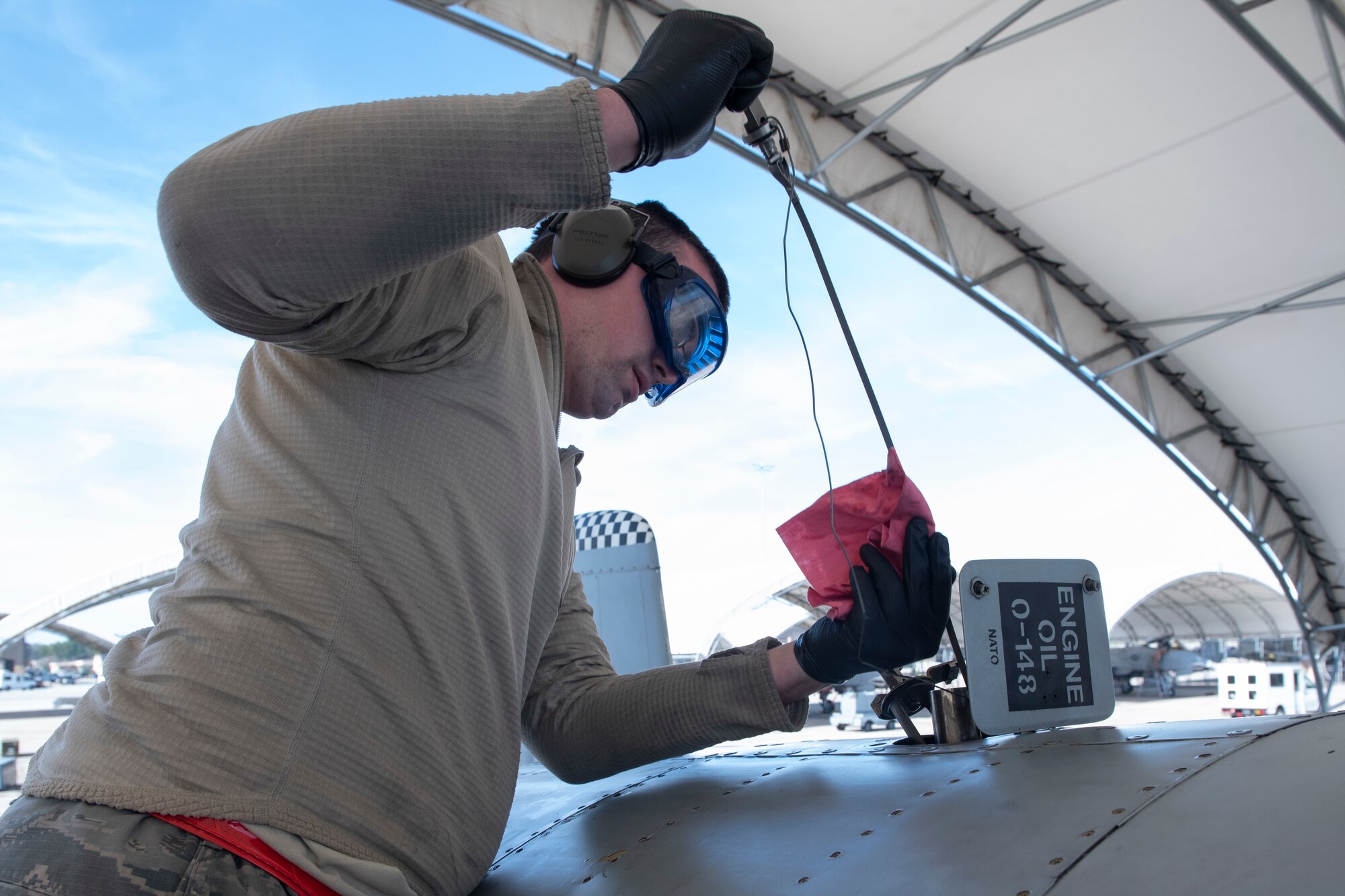 A photo of an Airman placing a dipstick in A-10C Thunderbolt II oil to determine its levels during a joint oil analysis.