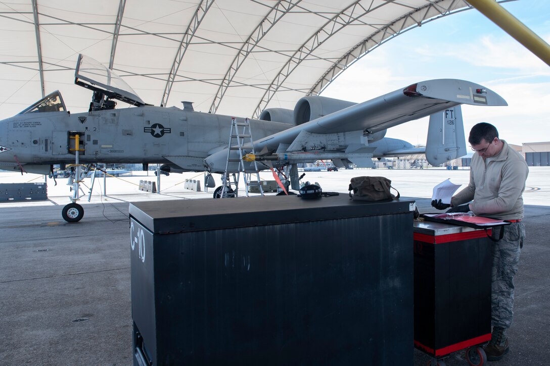 A photo of an Airman filling out a form 2026 after extracting oil from an A-10C Thunderbolt II.