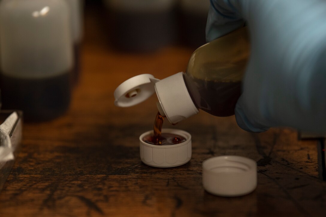 A photo of an Airman pouring oil in a cap.