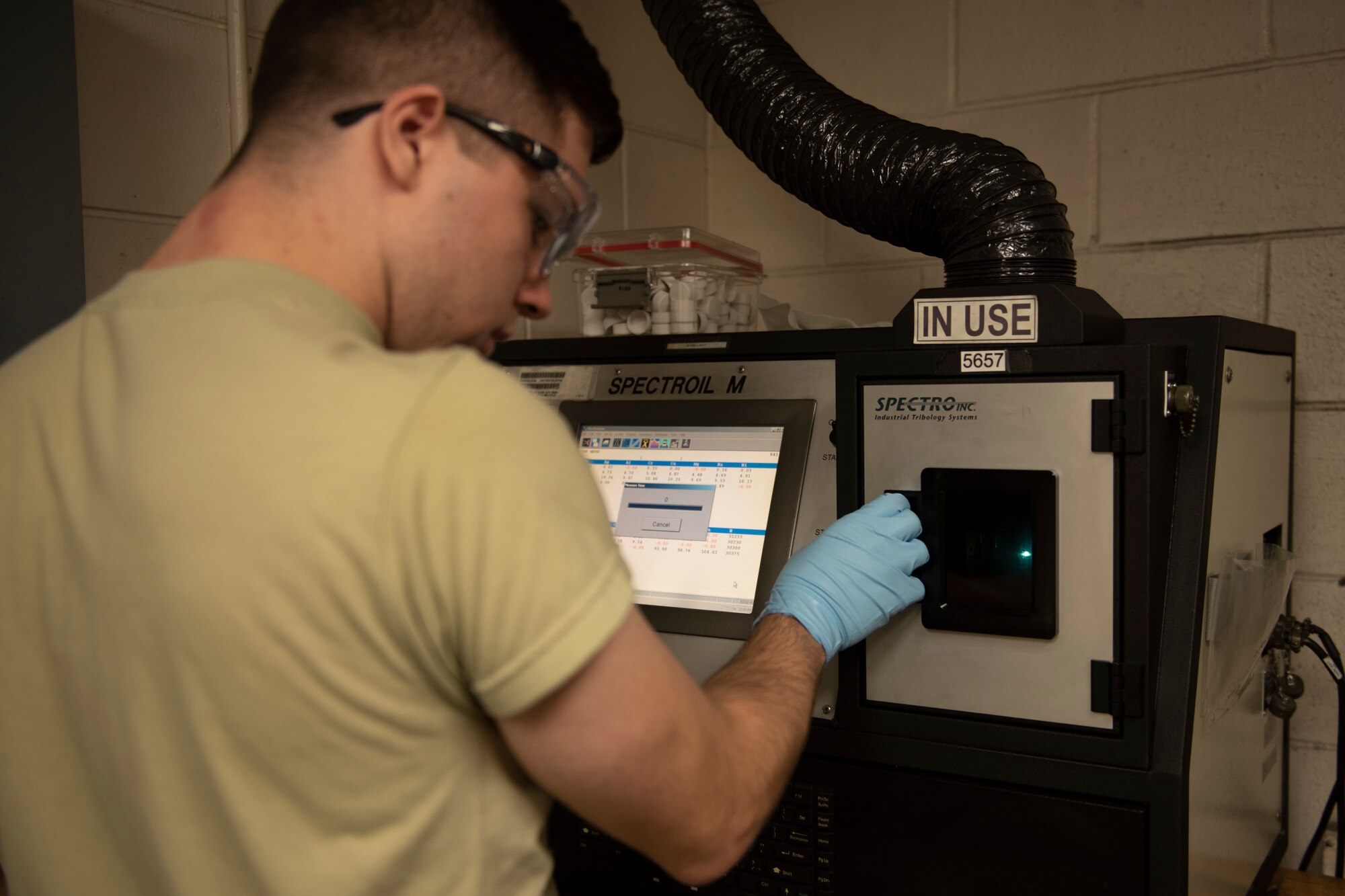 A photo of an Airman burning aircraft oil in a spectrometer.
