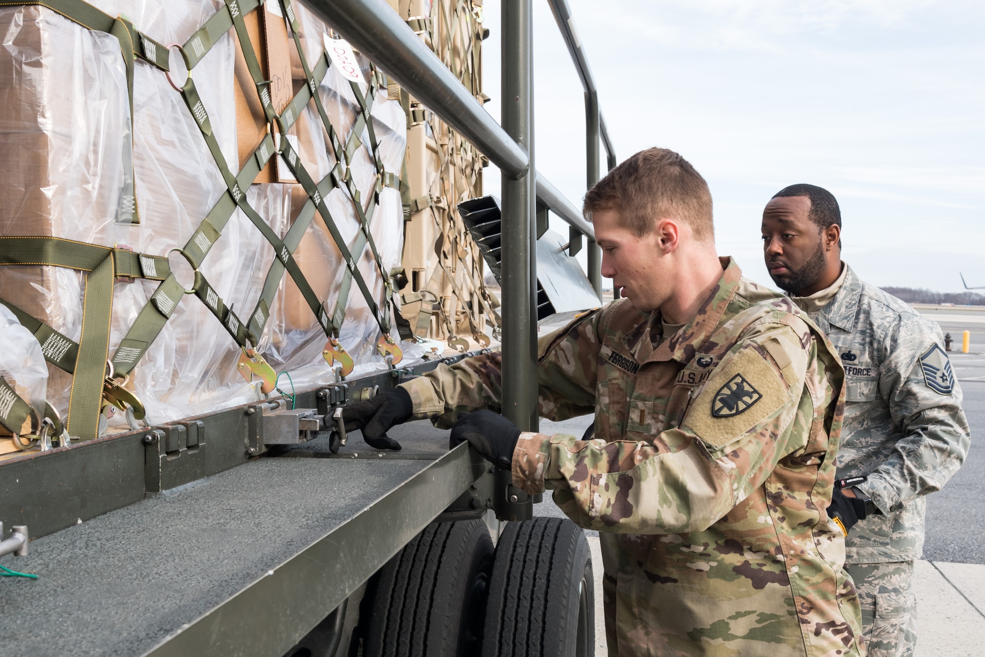 Air Force Master Sgt. Gerard Carry, 436th Aerial Port Squadron ramp operations noncommissioned officer in charge, observes Army 2nd Lt. Mackenzie Ferguson, 622nd Movement Control Team movement officer, Joint Base Langley-Eustis, Va., engage a cargo pallet lock on a 60-ton K-loader Jan. 10, 2020, on Dover Air Force Base, Del. In a scheduled joint partnership training event, 16 members from the 622nd MCT came to Dover AFB for cargo and personnel processing training. (U.S. Air Force photo by Roland Balik)
