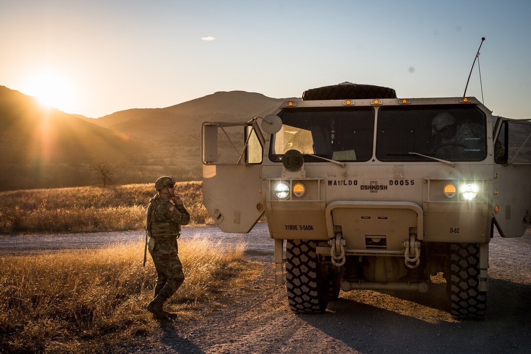 A soldier stands next to a military vehicle.