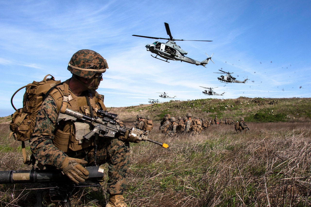 Marines watch as a group of helicopters prepare to land.