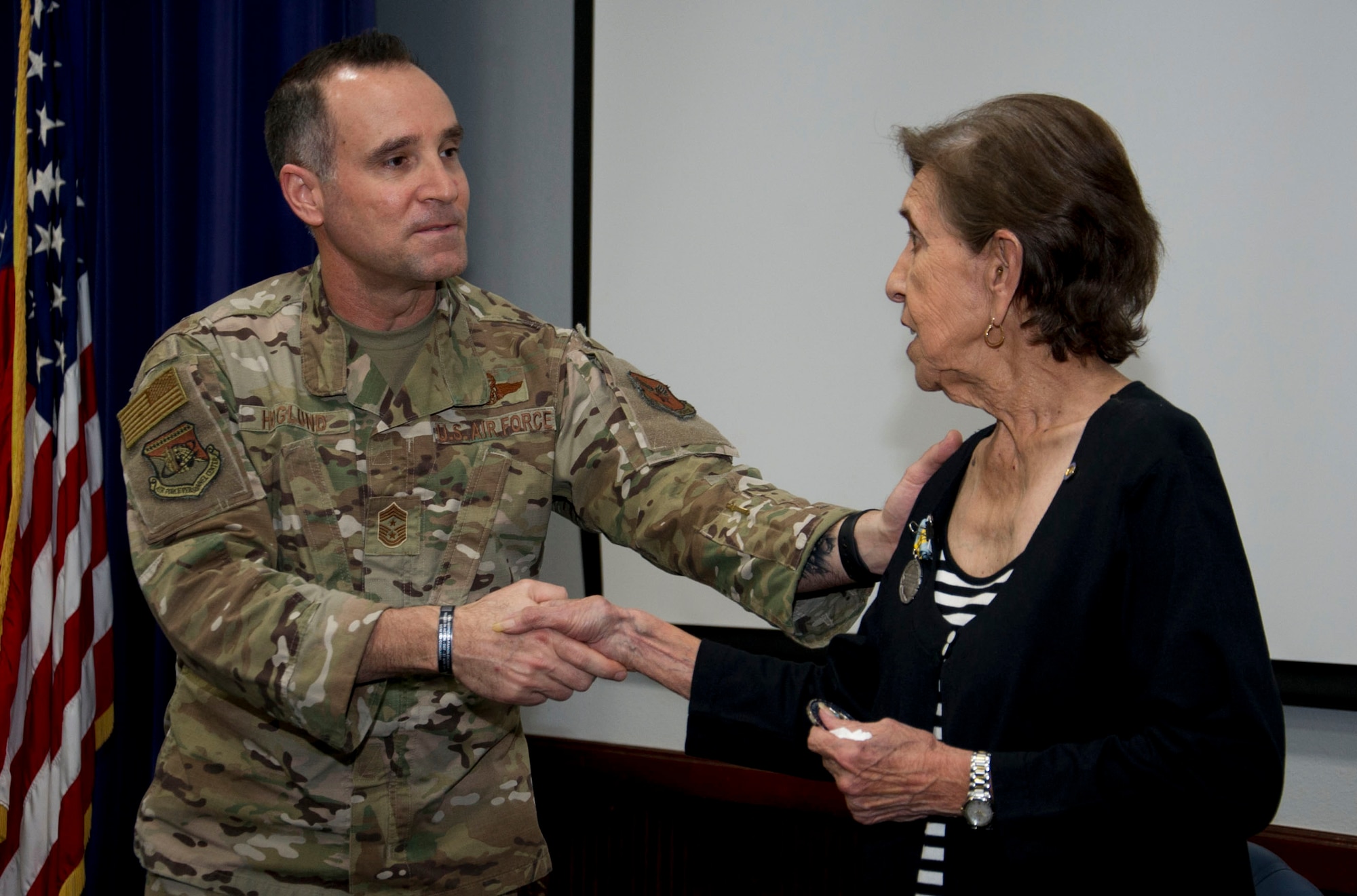 The Air Force’s Personnel Center’s command Chief Master Sgt. Daniel L. Hoglund congratulates Mary O. Price, with a handshake, following her retirement from federal service of 52 years.