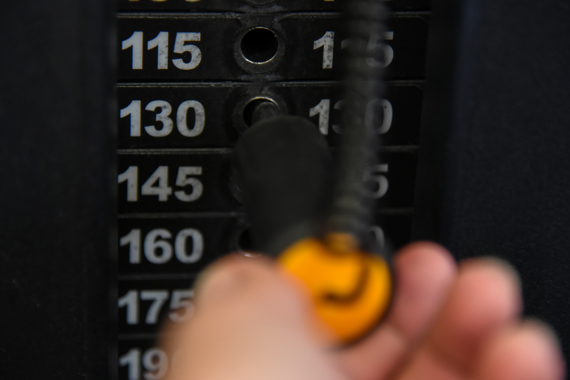 A person selects the weight on a weight machine.