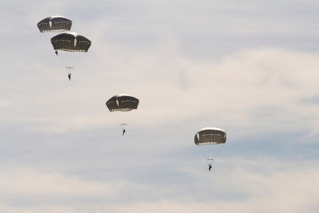 Six soldiers descend under open parachutes.