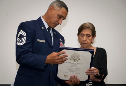Chief Master Sgt. Clinton Wilkerson, friend and presiding official of Mary Price’s retirement ceremony, presents her with the certificate of service during her ceremony.