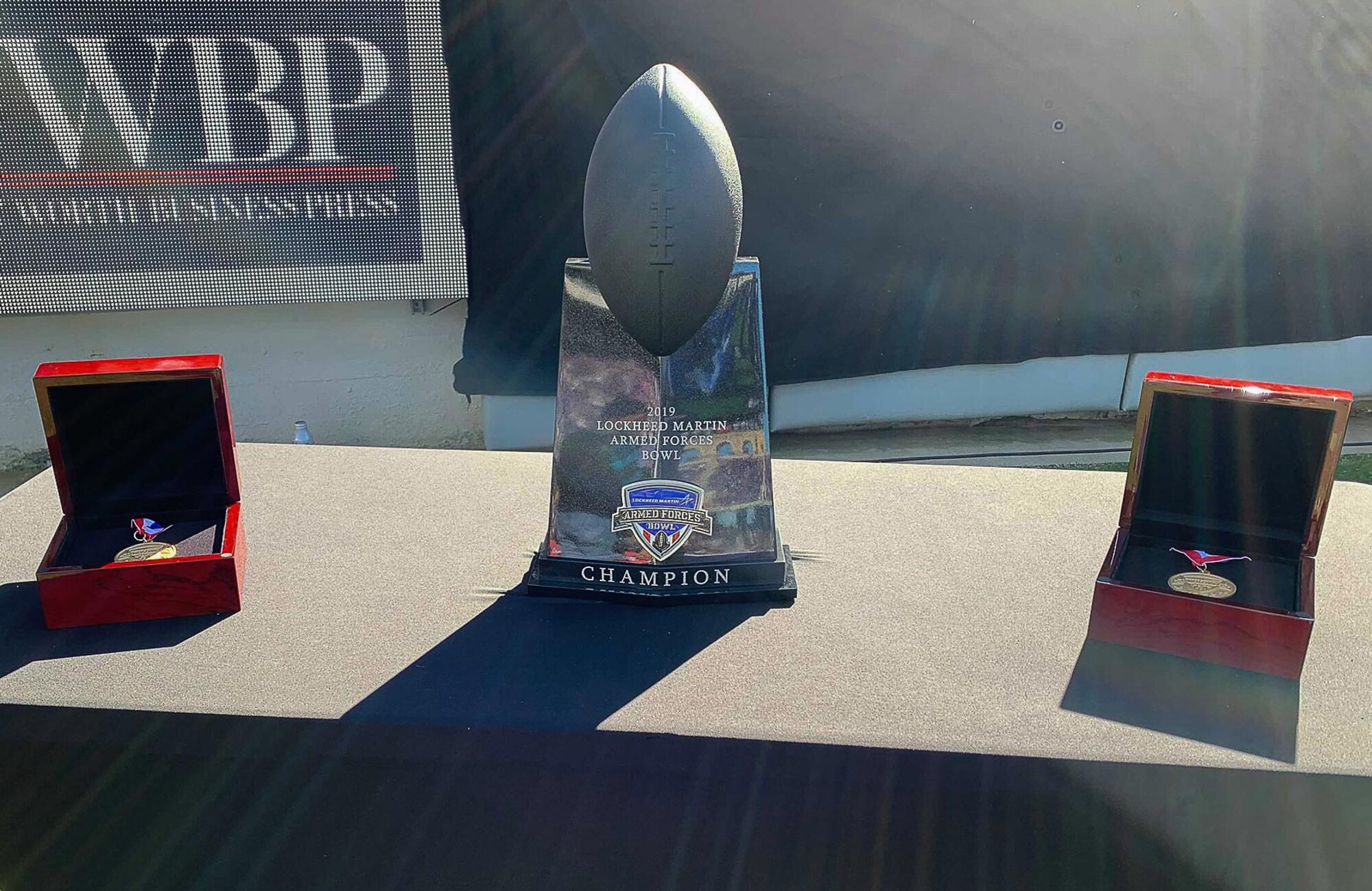 The trophy for the Lockheed Martin Armed Forces Bowl, which is made of decommissioned metal parts from each military branch, stands between the two player of the game medals wait to be presented at the conclusion of the game on January 4, 2020 in Fort Worth, Texas. Tulane University beat the University of Southern Mississippi 30 – 13. (U.S. Air Force photo by Capt. Jessica Gross)