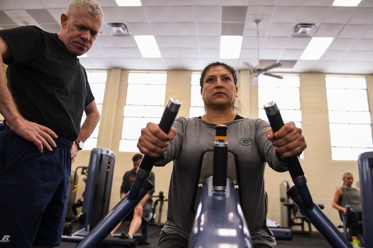 A person learns lifting techniques for the seated row weight machine.