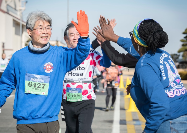 A runner in a 5K Race exchanges a high-five with a volunteer from the Yokota community during the 39th Annual Frostbite Run, Jan.19, 2020, at Yokota Air Base, Japan.
