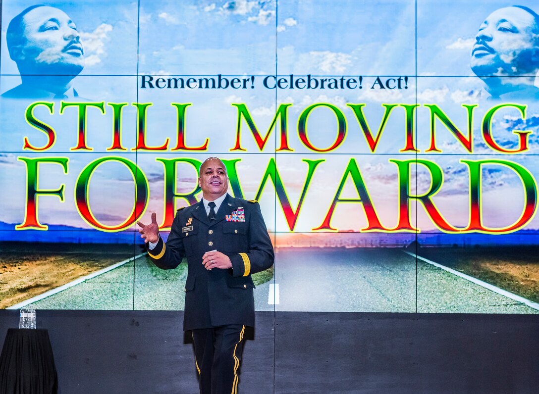 Man speaking in front of a large screen.