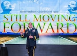 Man speaking in front of a large screen.