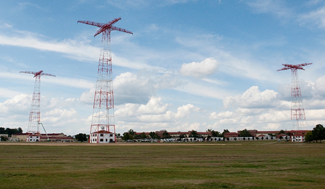 Three 250-foot red towers stand in the middle of a large field.