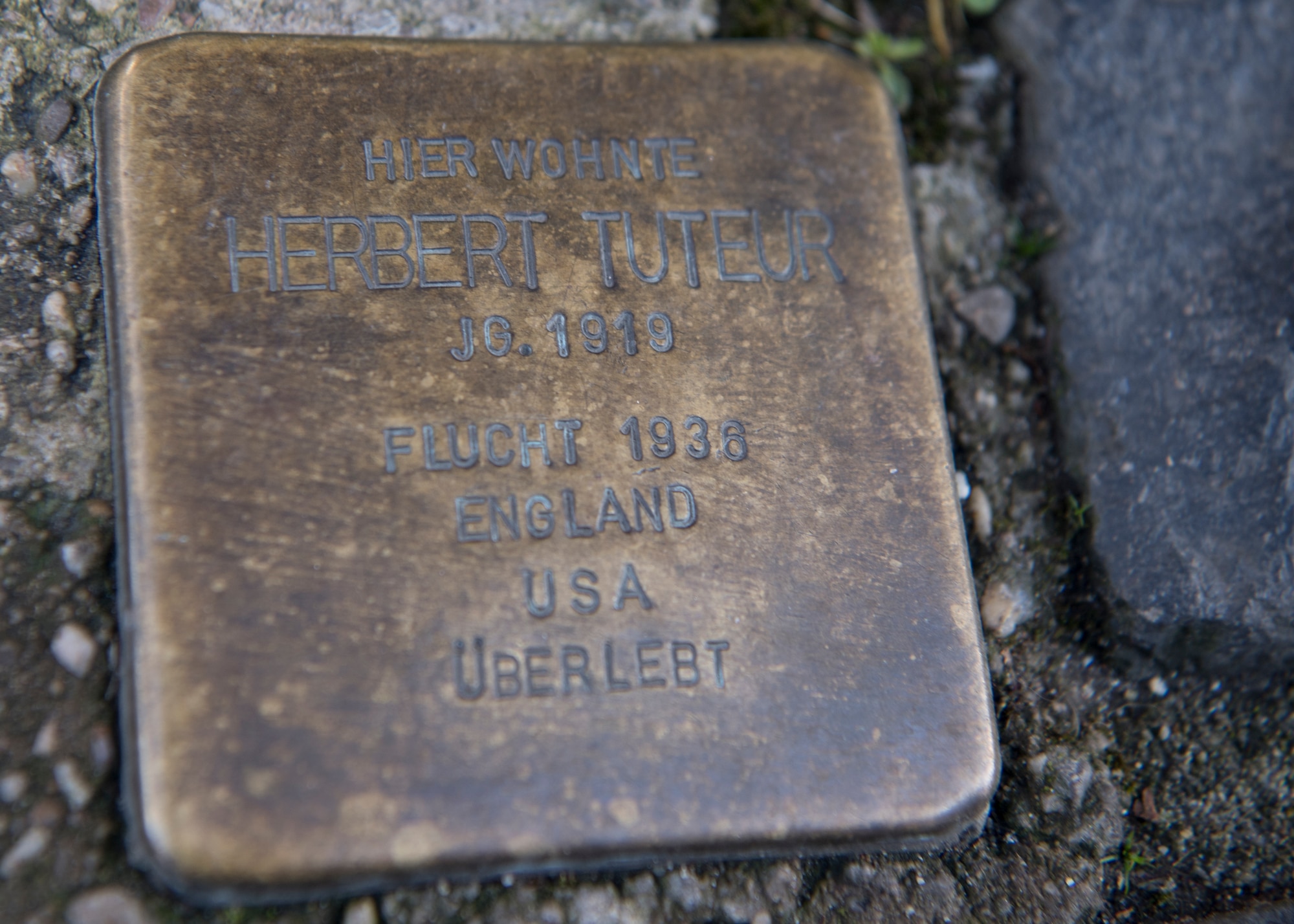 A small brass plaques called a “stumbling stone” sits in the pavement and depicts a holocaust victim’s name, date of birth, and date and place of death. Service members and their families can recognize victims of the Holocaust by learning about the Kaiserslautern memorials and local history throughout the year. (U.S. Air Force photo by Staff Sgt. Kirby Turbak)