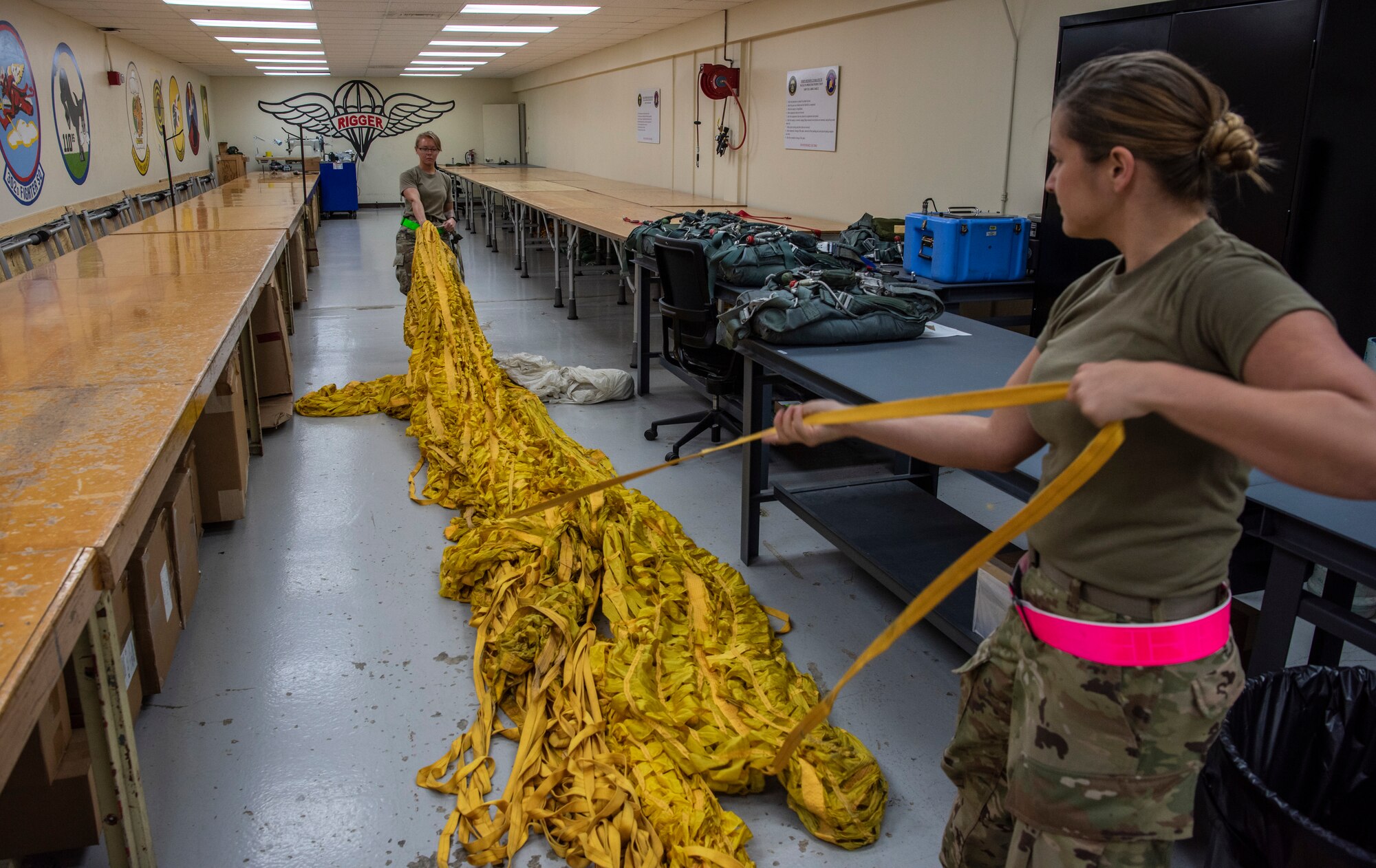 Senior Airman Brise Eble (left) and Senior Airmen Amanda Vigar, 69th Expeditionary Bomb Squadron aircrew flight equipment journeymen, unroll a deceleration parachute at Andersen Air Force Base, Guam, Jan. 16, 2020.