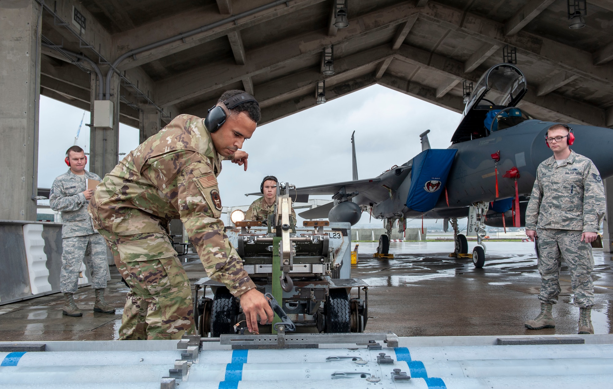 U.S. Air Force Staff Sgt. Jacob Wigfall, 44th Aircraft Maintenance Unit load crew chief, signals to Senior Airman Edward Bennett, 44th AMU load crew member, while loading an AIM-120 advanced medium-range air-to-air missile onto an MJ-1C lift truck during the annual weapons load competition at Kadena Air Base, Japan, Jan. 17, 2020. This competition featured four teams competing for the 18th Wing’s best load crew of the year. (U.S. Air Force photo by Naoto Anazawa)